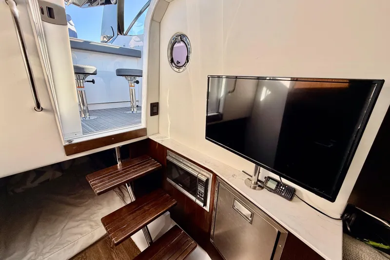 Slide: The Image of Interior of 2022 New Cruiser Yachts GLS 38 with TV, microwave, and stairs to deck. - 48