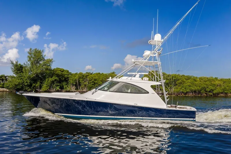 Slide: The Image of 2021 Viking 52 Sport Tower yacht cruising on a sunny day, surrounded by lush greenery. - 6