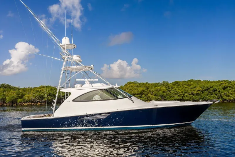 Slide: The Image of 2021 Viking 52 Sport Tower yacht cruising on calm waters under a clear blue sky. - 19