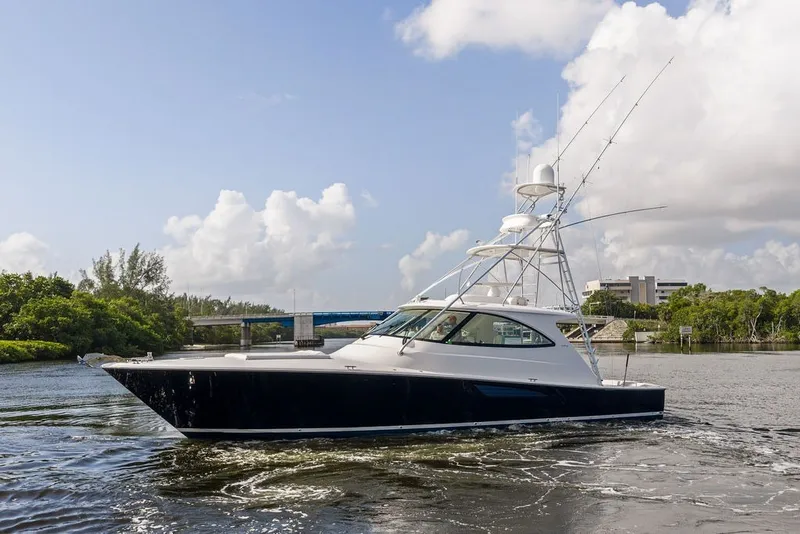 Slide: The Image of 2021 Viking 52 Sport Tower yacht cruising on a scenic waterway under a blue sky. - 11