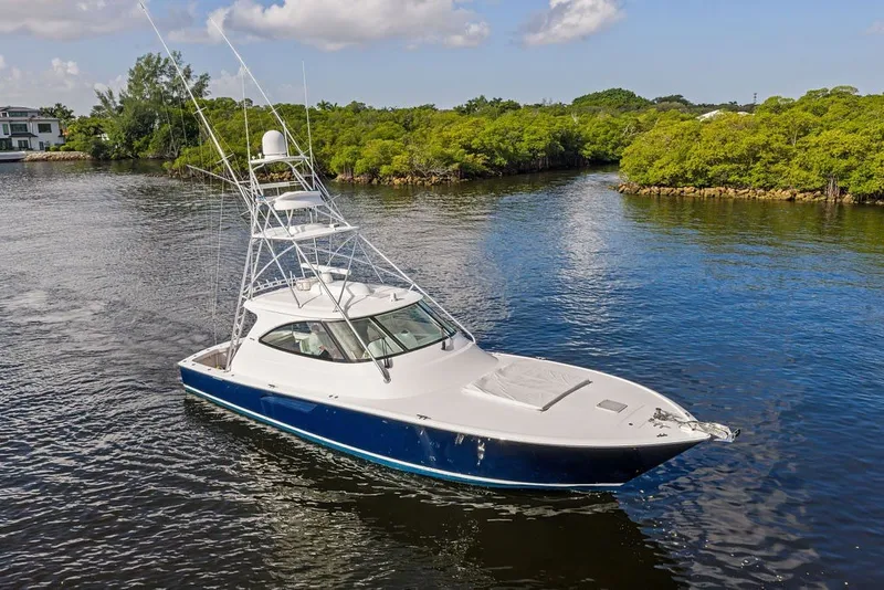 Slide: The Image of 2021 Viking 52 Sport Tower yacht cruising on a serene waterway, surrounded by lush greenery. - 20