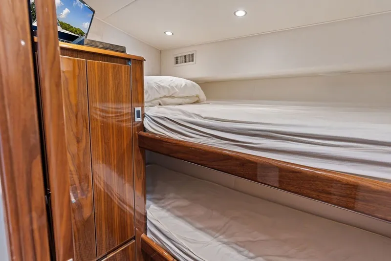 Slide: The Image of 2021 Viking 52 Sport Tower interior with wooden cabinetry and cozy bunk beds. - 58