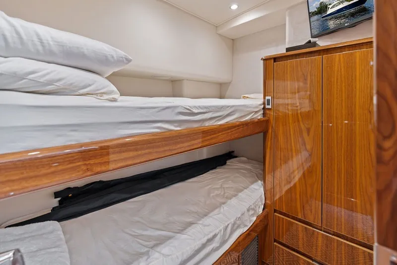 Slide: The Image of Interior of 2021 Viking 52 Sport Tower with wooden bunk beds and storage. - 57