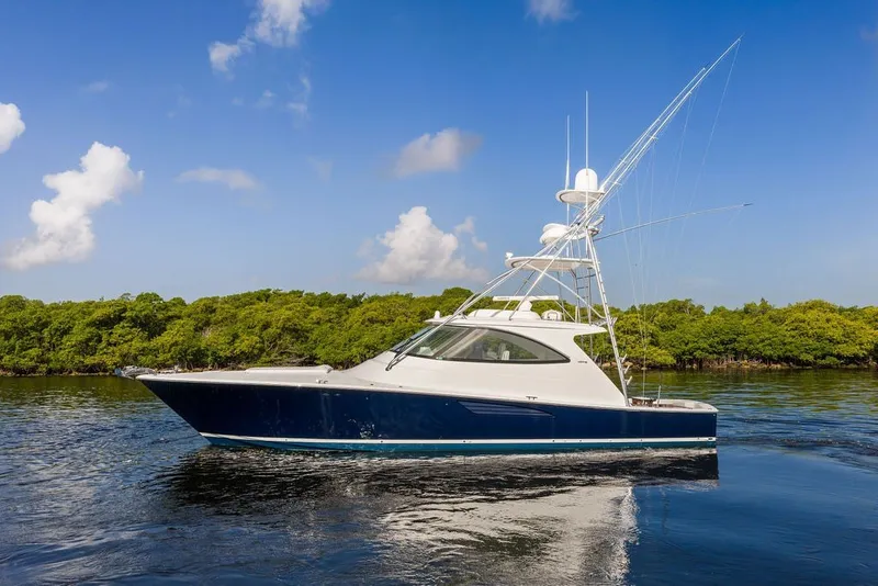 Slide: The Image of 2021 Viking 52 Sport Tower yacht cruising on calm waters under a clear blue sky. - 5