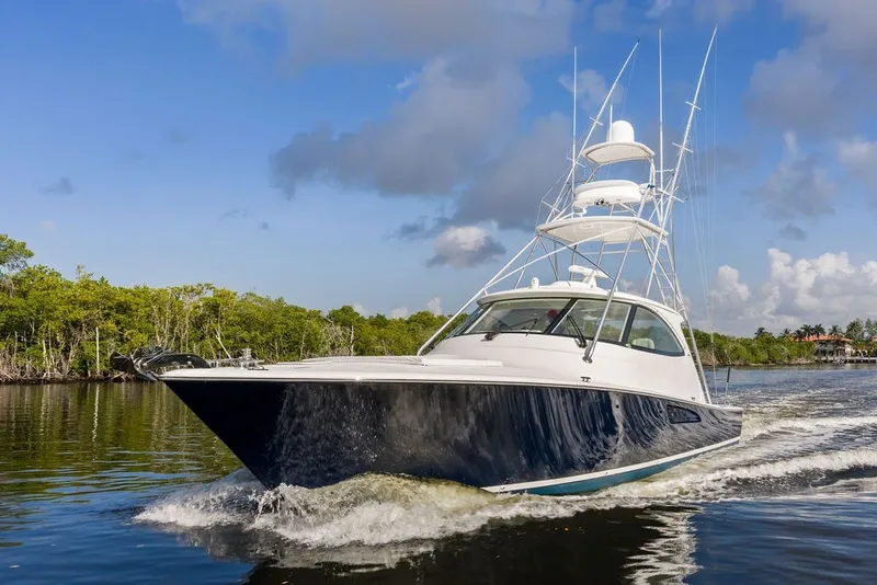 Slide: The Image of 2021 Viking 52 Sport Tower cruising on a scenic waterway under a clear sky. - 10