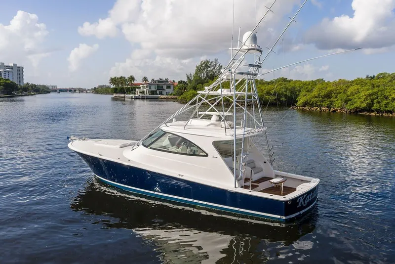 Slide: The Image of 2021 Viking 52 Sport Tower yacht cruising on a scenic waterway with lush greenery. - 13