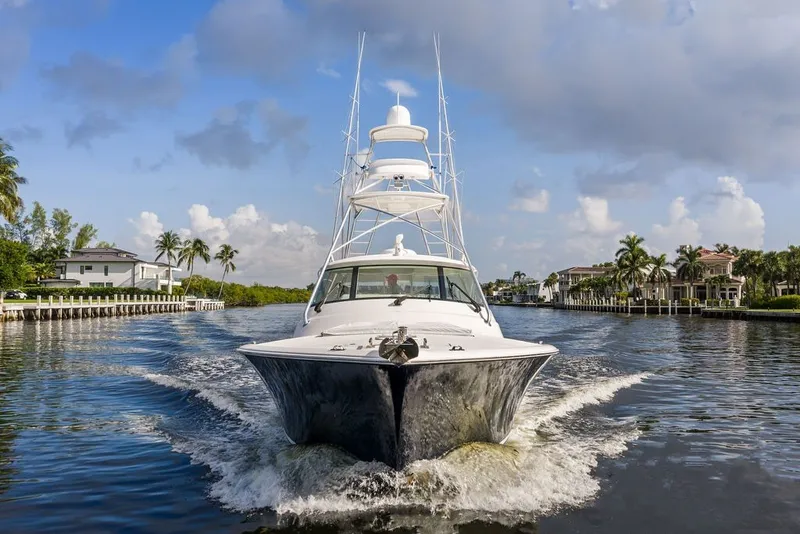 Slide: The Image of 2021 Viking 52 Sport Tower cruising on a scenic waterway with palm trees. - 2