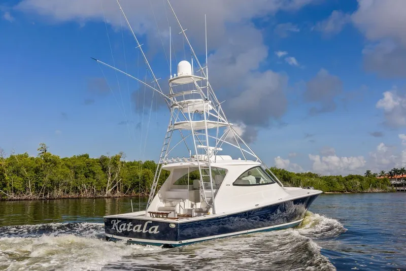 Slide: The Image of 2021 Viking 52 Sport Tower yacht cruising on a sunny day with lush greenery. - 24