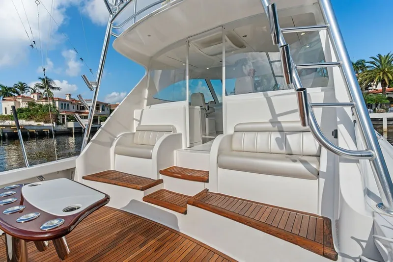Slide: The Image of 2021 Viking 52 Sport Tower yacht deck with seating and ladder, docked near waterfront homes. - 28