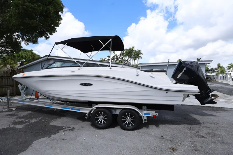 Slide: The Image of 2023 Sea Ray SPX 230 Outboard boat on trailer, parked outdoors under blue sky. - 2