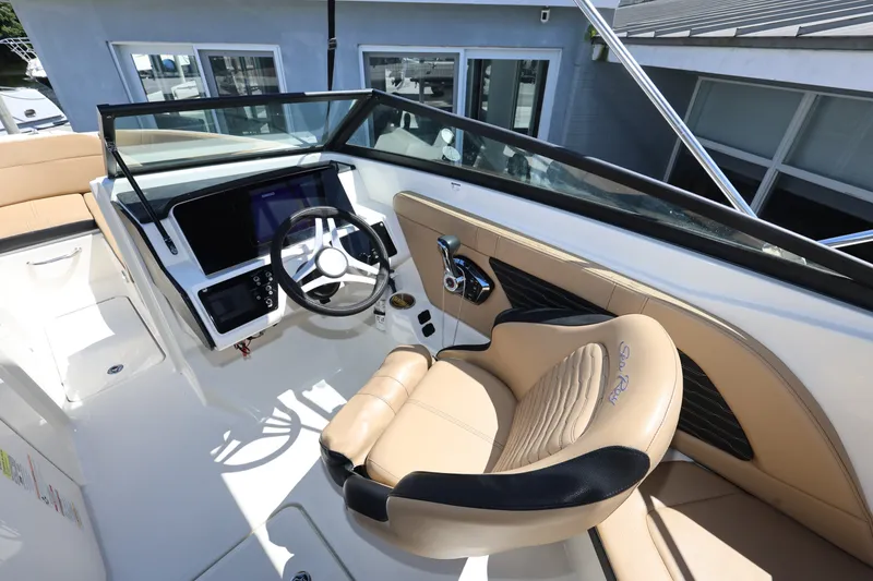 Slide: The Image of 2023 Sea Ray SPX 230 Outboard cockpit with steering wheel and beige seating. - 12
