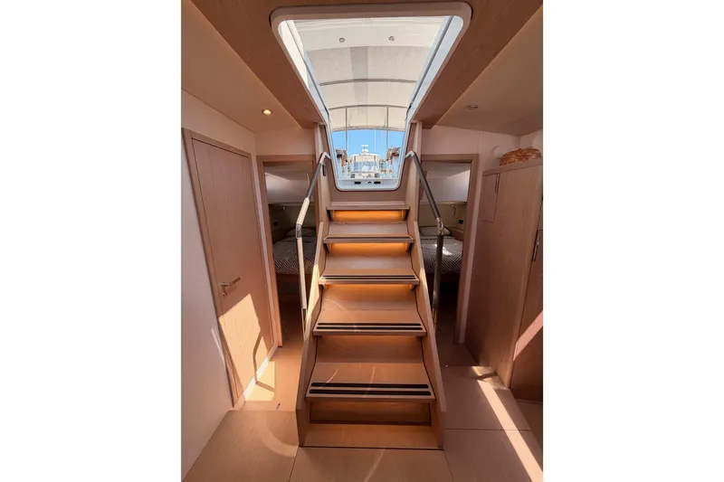 Slide: The Image of Interior view of 2022 Beneteau Oceanis Yacht 54, featuring wooden stairs and cabin access. - 90