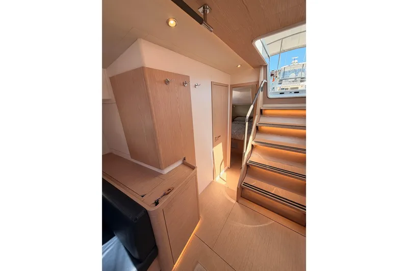 Slide: The Image of Interior of 2022 Beneteau Oceanis Yacht 54, featuring wooden cabinetry and illuminated stairs. - 61
