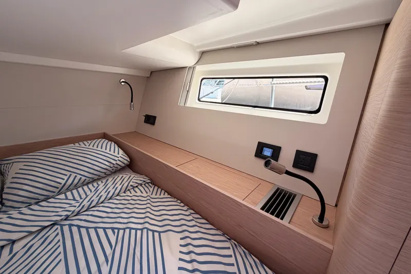 Slide: The Image of Luxurious cabin interior of 2022 Beneteau Oceanis Yacht 54 with striped bedding and modern fixtures. - 58
