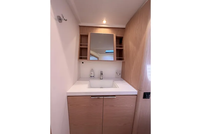 Slide: The Image of Modern bathroom vanity on 2022 Beneteau Oceanis Yacht 54, featuring sleek wood cabinetry and mirror. - 84