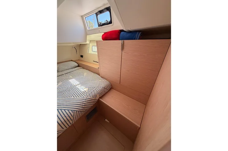Slide: The Image of Interior cabin of 2022 Beneteau Oceanis Yacht 54 with striped bedding and wooden cabinetry. - 57