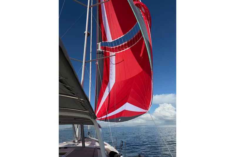 Slide: The Image of 2022 Beneteau Oceanis Yacht 54 sailing with vibrant red spinnaker against blue sky. - 96