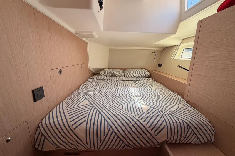 Slide: The Image of Cozy cabin interior of 2022 Beneteau Oceanis Yacht 54 with striped bedding. - 56