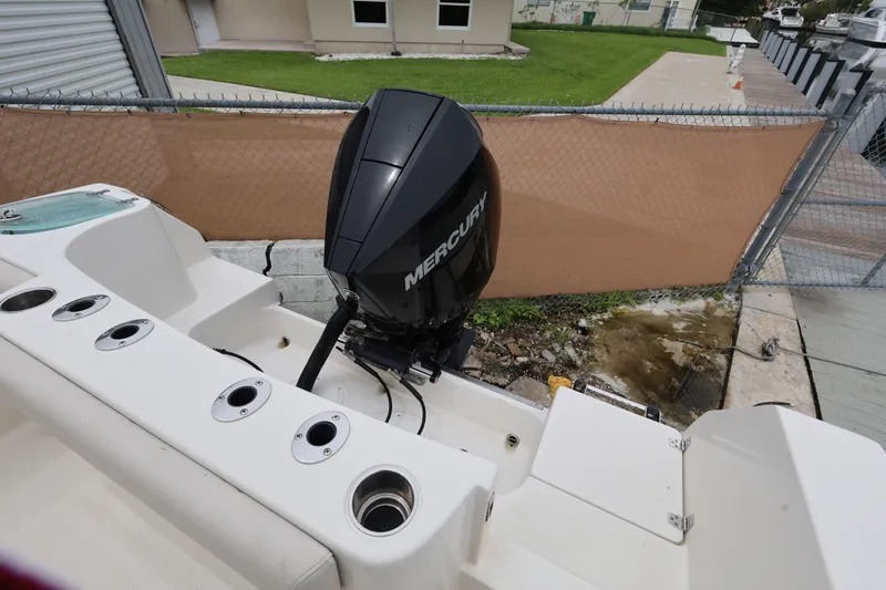 Slide: The Image of 2022 Sailfish 242 CC boat with Mercury outboard motor, docked near a fenced area. - 18
