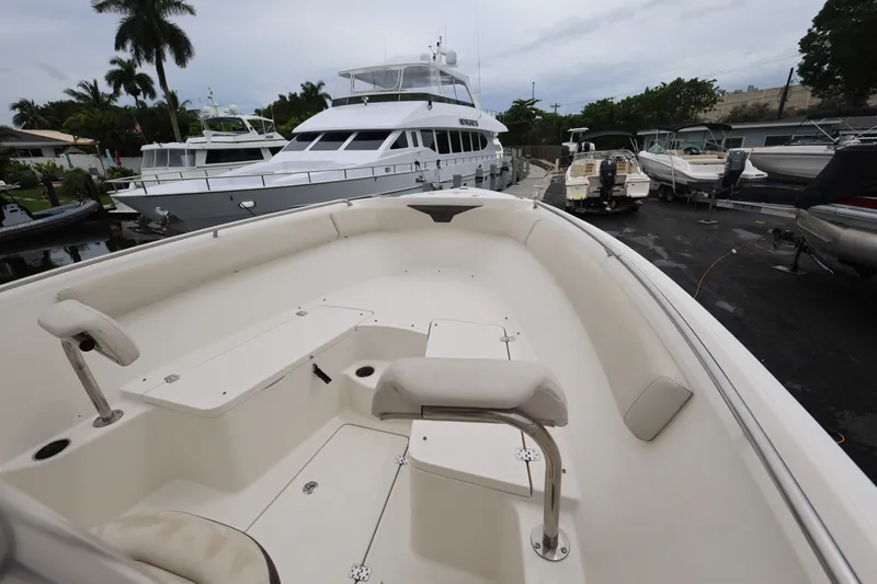 Slide: The Image of 2022 Sailfish 242 CC boat docked, surrounded by other vessels and palm trees. - 13