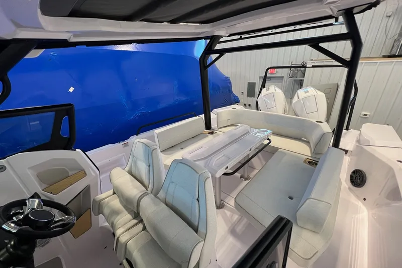 Slide: The Image of 2027 Axopar 29 Sun-Top boat interior with seating and steering wheel in a showroom. - 32