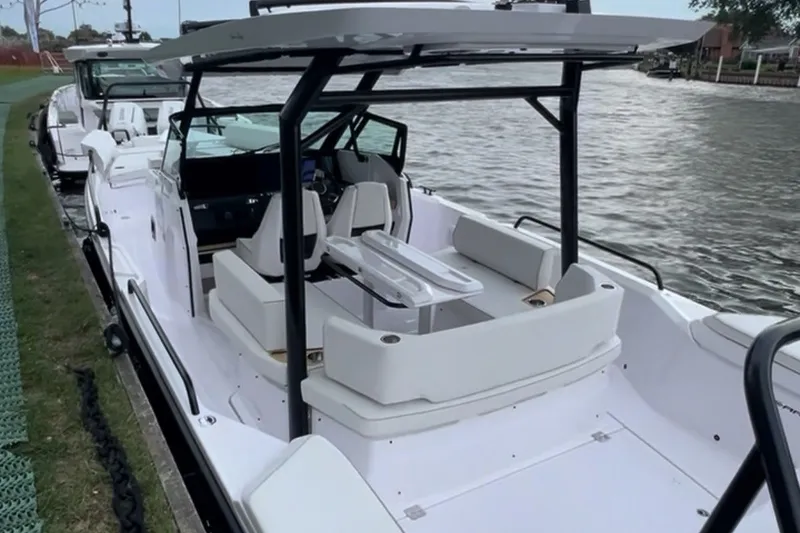 Slide: The Image of 2027 Axopar 29 Sun-Top boat docked by the water, showcasing sleek design and spacious seating. - 3