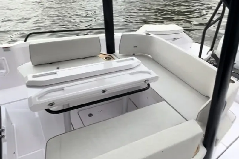 Slide: The Image of 2027 Axopar 29 Sun-Top boat interior with white seating and table, near water. - 6