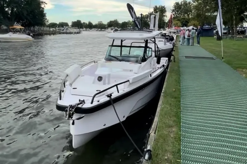 The Image of 2027 Axopar 29 Sun-Top boat docked by a riverside with lush greenery. - 1