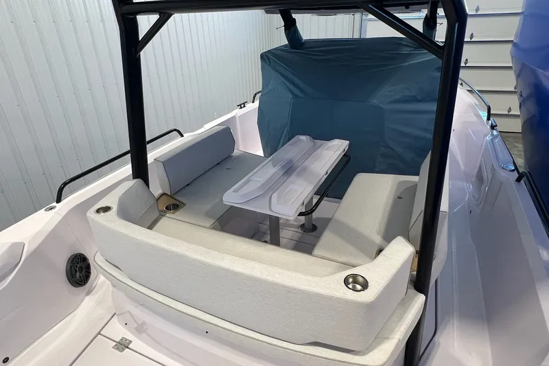 Slide: The Image of 2027 Axopar 29 Sun-Top boat interior with seating and table in a garage setting. - 14
