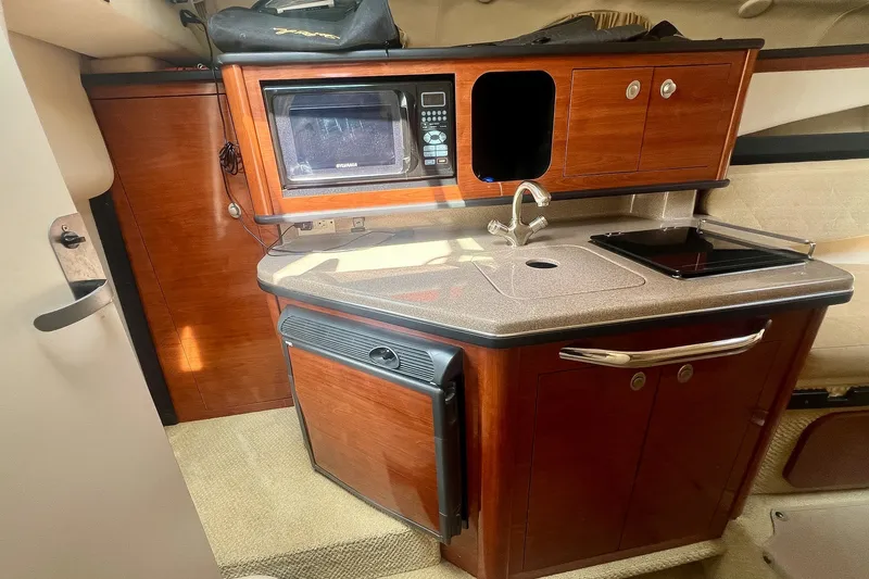 Slide: The Image of 2007 Sea Ray 270 Amberjack cabin kitchen with microwave, sink, and compact fridge. - 24