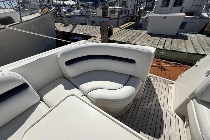 Slide: The Image of 2008 Sea Ray 38 Sundancer boat with white seating and wooden deck at a marina. - 128