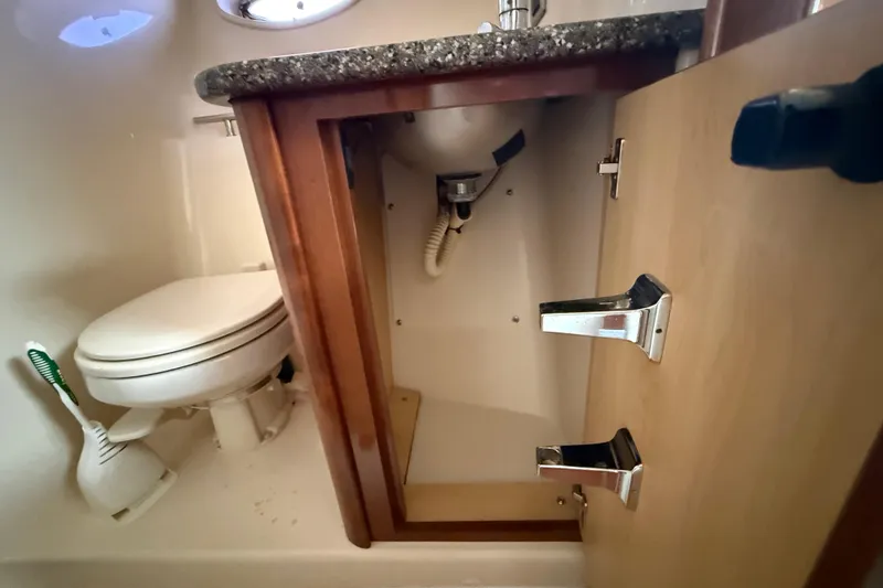 Slide: The Image of Bathroom interior of 2008 Sea Ray 38 Sundancer yacht, featuring toilet and open cabinet. - 56