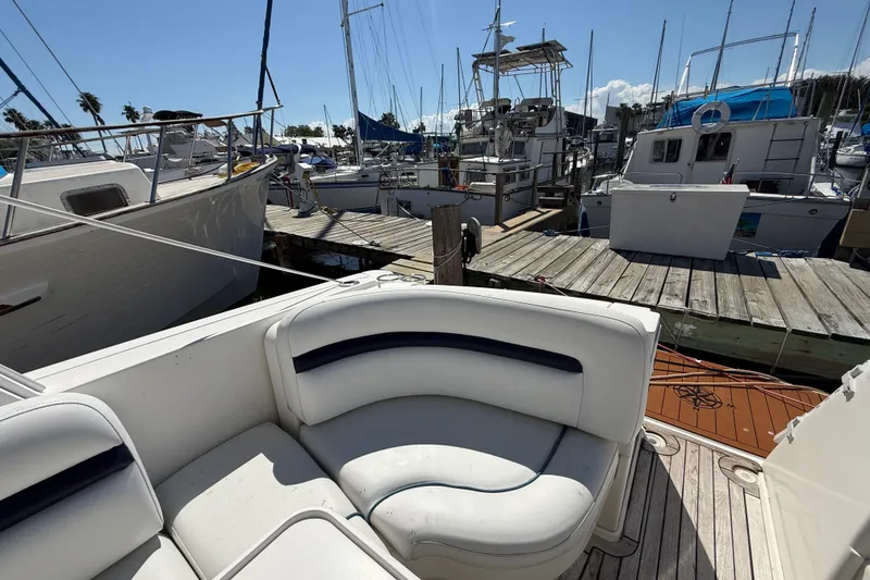Slide: The Image of 2008 Sea Ray 38 Sundancer at marina, featuring white seating and docked boats. - 129