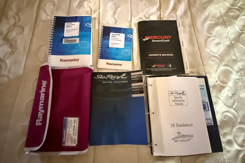 Slide: The Image of Manuals and booklets for 2008 Sea Ray 38 Sundancer on a quilted bedspread. - 40