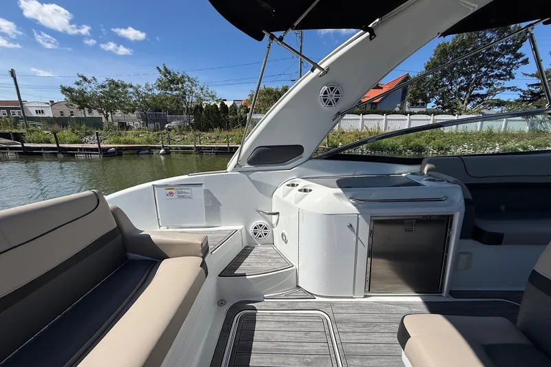 Slide: The Image of 2013 Formula 310 Bowrider interior with seating and kitchenette, docked by a scenic waterfront. - 22