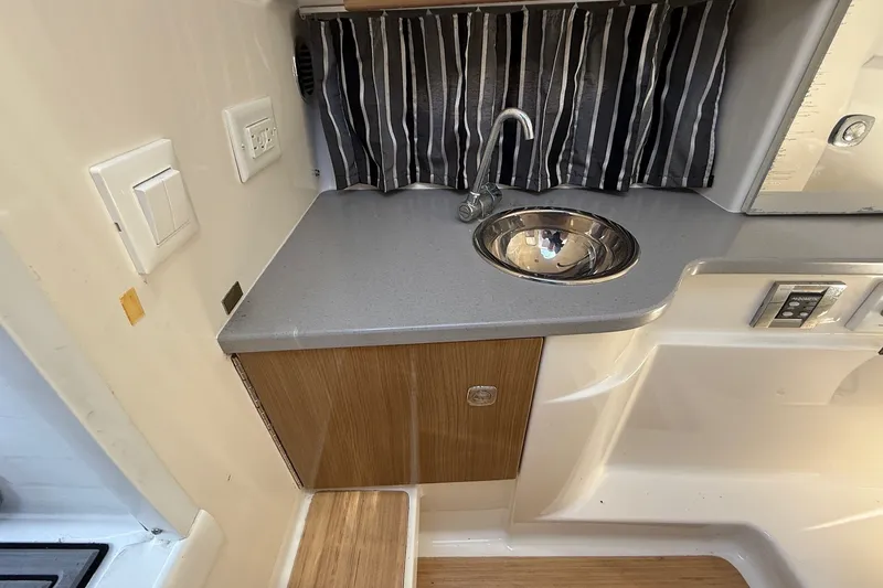 Slide: The Image of 2013 Formula 310 Bowrider interior with sink, countertop, and striped curtain. - 44
