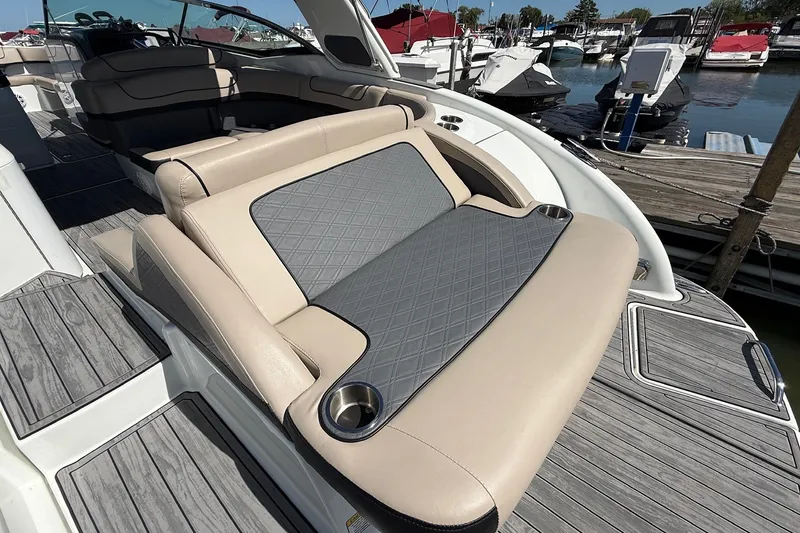 Slide: The Image of 2013 Formula 310 Bowrider boat interior with cushioned seating and cup holders at a marina. - 16