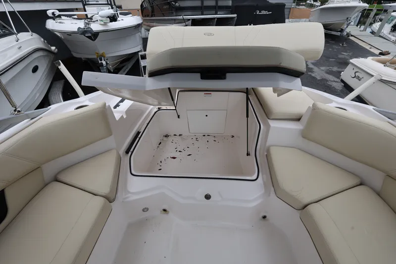 Slide: The Image of 2020 Regal 21 OBX boat interior with open storage compartment and beige seating. - 19