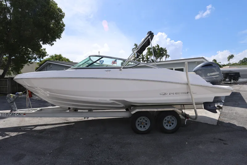 Slide: The Image of 2020 Regal 21 OBX boat on trailer with Yamaha outboard motor, parked outdoors. - 6