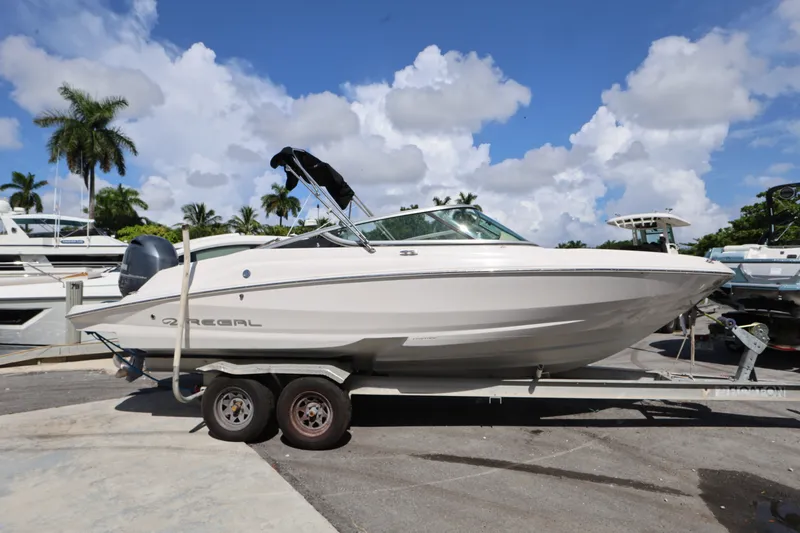 Slide: The Image of 2020 Regal 21 OBX boat on trailer, parked outdoors under a clear blue sky. - 1