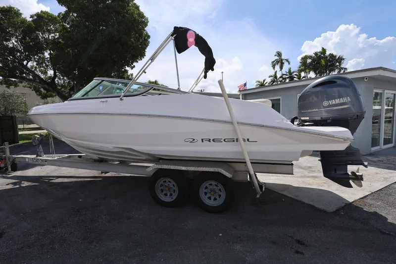 Slide: The Image of 2020 Regal 21 OBX boat on trailer with Yamaha outboard motor, parked outdoors. - 5