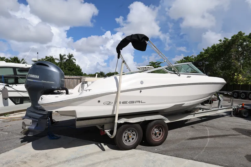 Slide: The Image of 2020 Regal 21 OBX boat on trailer with Yamaha outboard motor, parked outdoors. - 2