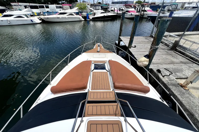 Slide: The Image of Ein Boot liegt in einem Hafen, umgeben von anderen Booten. Es hat ein Holzdeck und braune Polster. - 22
