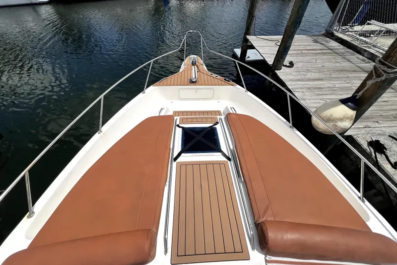 Slide: The Image of Een slanke boot met bruine kussens ligt aangemeerd aan een houten steiger op het water. - 23