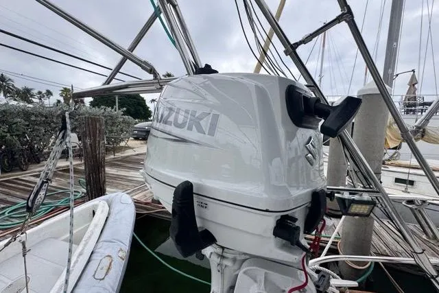 Slide: The Image of Suzuki outboard motor on a 1996 Beneteau 50 sailboat, docked with inflatable dinghy nearby. - 47