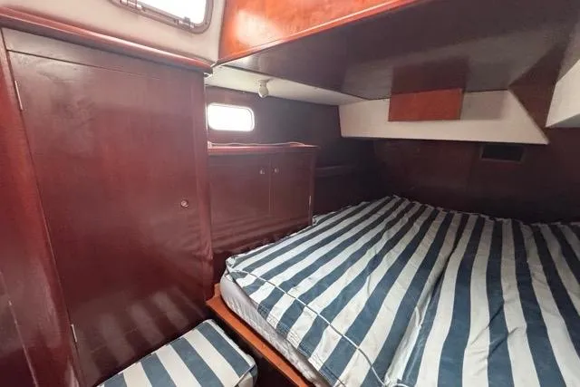 Slide: The Image of Cabin interior of 1996 Beneteau 50 sailboat with striped bedding and wooden cabinetry. - 97