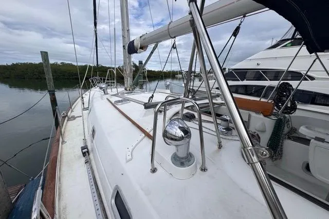 Slide: The Image of 1996 Beneteau 50 sailboat deck with stainless steel fittings and calm marina backdrop. - 12