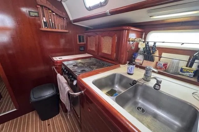 Slide: The Image of Galley kitchen in 1996 Beneteau 50 yacht with wooden cabinetry and dual sink. - 70