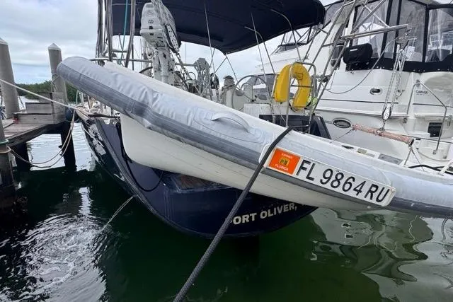 Slide: The Image of 1996 Beneteau 50 sailboat docked, featuring inflatable dinghy and registration FL 9864 RU. - 3