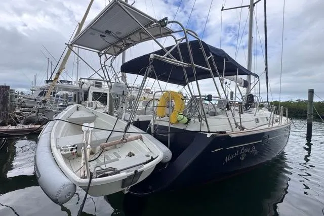 Slide: The Image of Beneteau 50 sailboat, 1996 model, docked with dinghy, overcast sky. - 1
